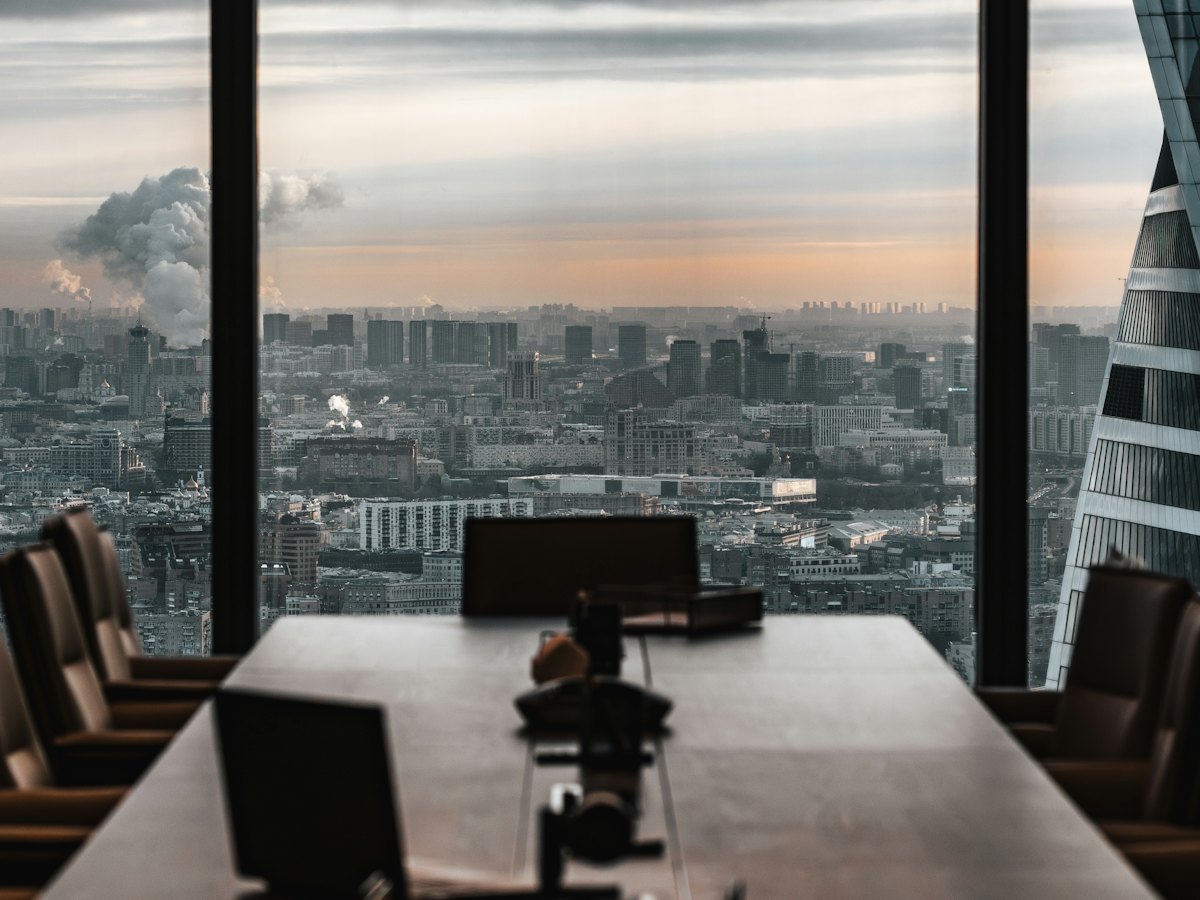 Table de réunion face à une ville sous un ciel lourd, une bande de lumière à l’horizon