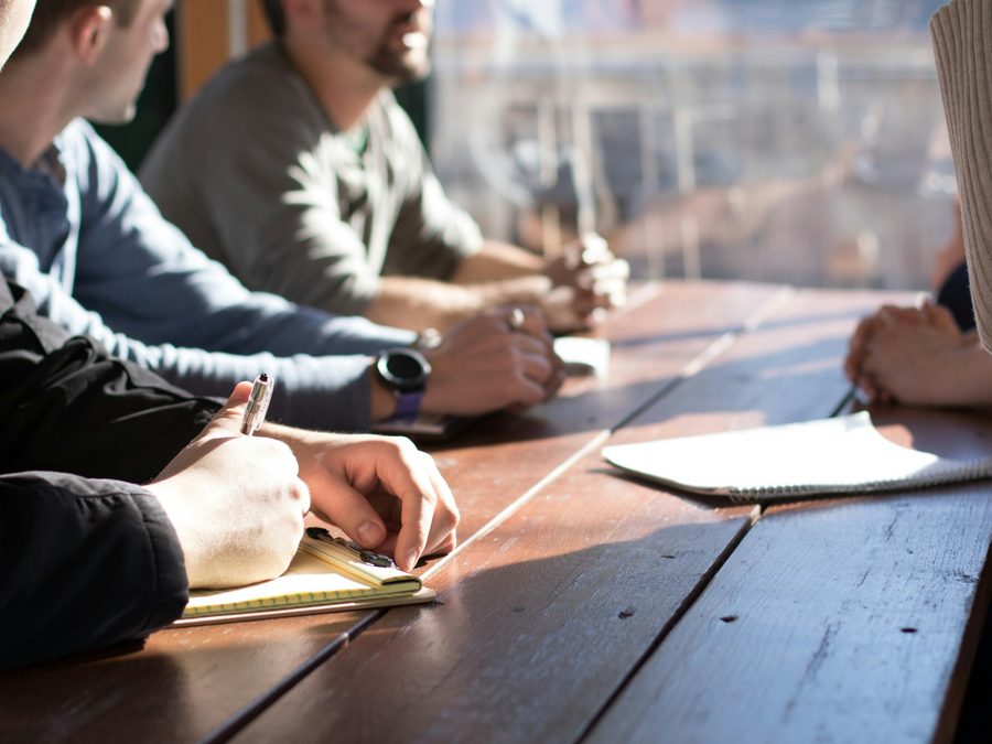 Plusieurs participants prenant des notes autour d'une table de travail, à contre-jour